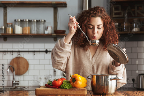 Photo of pretty caucasian woman holding cooking ladle spoon while eating soup at home