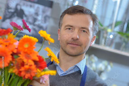 male flower seller holds flowers in his shop