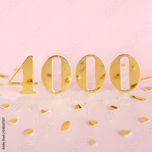 The number 4000 in golden numbers on a pink background and golden confetti. Space for text...