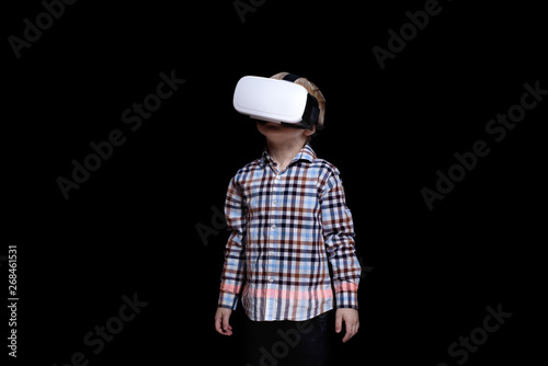 Little blond boy with glasses of virtual reality. Plaid shirt. Black background
