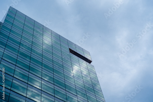 Low Angle Of Modern Glass Skyscraper Against Vivid Blue Sky with Clouds