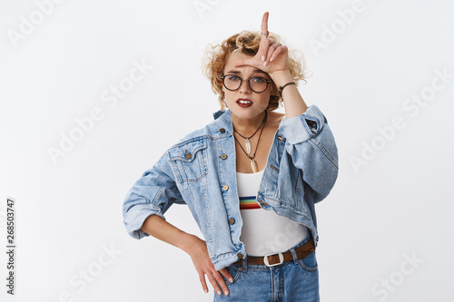 Girl looking with dismay at losers. Portrait of arrogant and confident good-looking stylish woman with short blond haircut mocking rival showing L letter on forehead and grimacing like snob