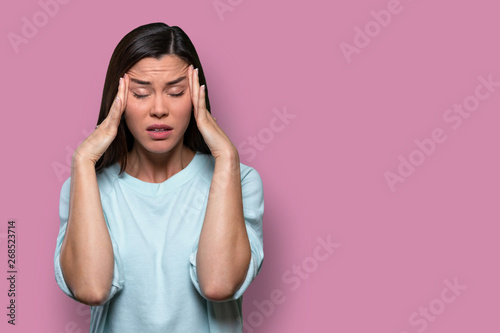 Woman overwhelmed with stress and concern, confusion and doubt, hands to head, on pink background copy space