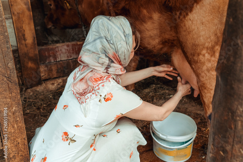 woman milkmaid milking a cow, farm