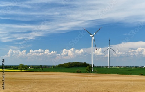 Elektrownia wiatrowa w polu na tle pięknych kłębiastych chmur