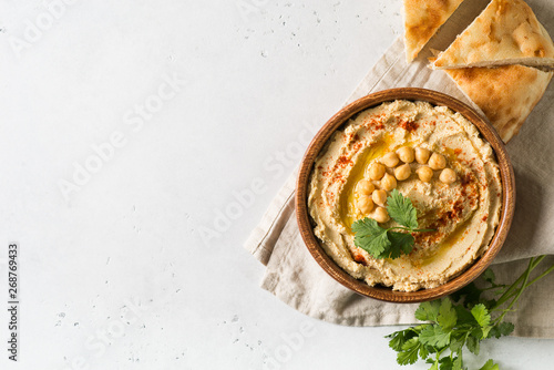 Hummus dip with chickpea, pita and parsley in wooden plate on white background