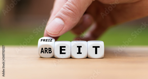 Hand dreht einen Würfel und ändert das Wort "Arbeit" in "Freizeit".