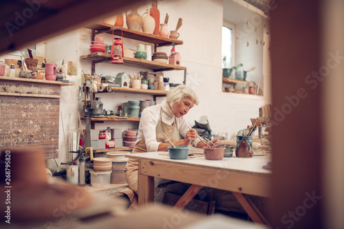 Nice grey haired aged woman painting pictures