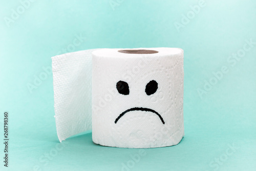 White toilet paper with sad face. Creative concept constipation, indigestion, digestion problem.
