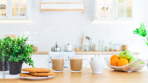 Two cups of morning coffee, cookies and fruit on the kitchen table. Good morning or breakfast concept.