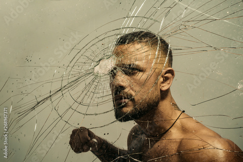 Determination to succeed. Muscular man having inner determination and commitment to break glass wall. Determined latino man removing obstacle with determination and confidence. Determination concept