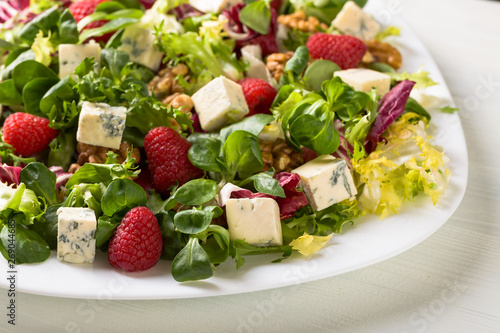 Green salad with blue cheese, raspberry and walnuts.