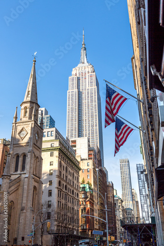View of Empire State Building and Marble Collegiate Church with American flags from 5th Avenue 28th st