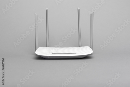 White modern Wi-Fi router with four antennas on a gray background.
