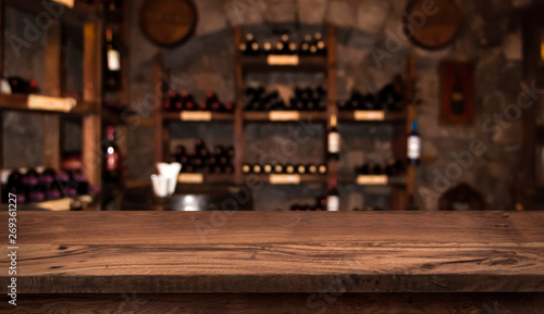 Defocused dark wine cellar background with wooden table in front