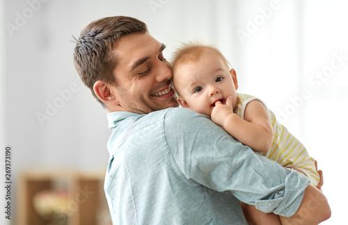 family, fatherhood and people concept - happy father holding little baby daughter at home