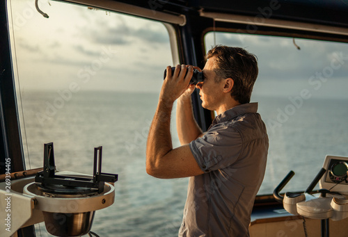 Navigational officer lookout on navigation watch looking through binoculars. Marine industry. COLREG collision regulations