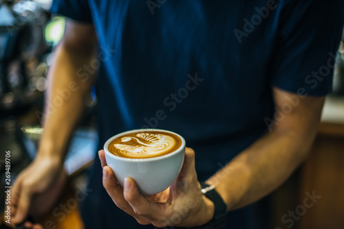 Close-up of hands barista make latte coffee art paint