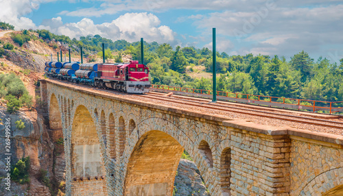 Red passenger diesel train moving at the bridge - Varda railway bridge, Adana Turkey