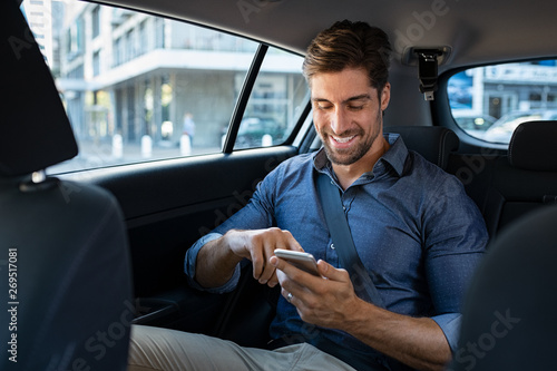 Happy business man in car using phone