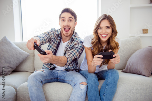 Portrait of his he her she two person nice-looking attractive lovely cheerful cheery positive guy lady playing online station having fun in light white style interior hotel house indoors