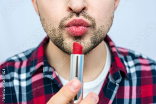 Portrait, bearded man, holding red lipstick, in his hand close to face, on camera, front view, close up