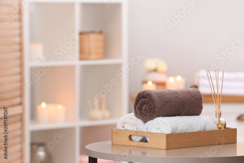 Tray with towels and reed air freshener on table in spa salon. Space for text