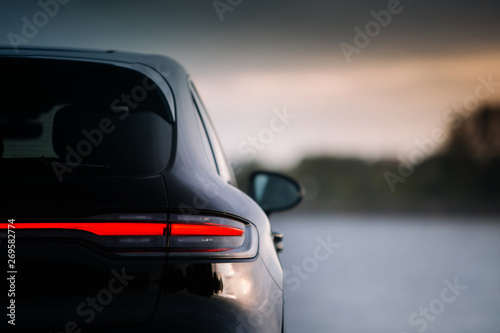 Modern suv car rear taillamp at evening near lake. LED tail lights is switched on during evening. Expensive and luxury crossover rear part with free space 