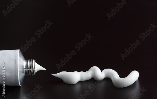 tube of white cream, ointment stroke squeezed out on black background