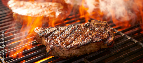 rib-eye steaks cooking on flaming grill panorama
