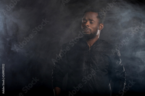 Young cool black man with disco ball over black background