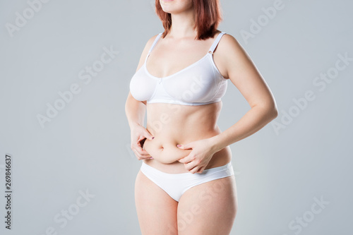 Woman with fat flabby belly, overweight female body on gray background