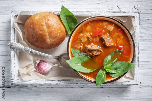 Bowl of goulash in box on white rustic table. Traditional hungarian meal. 