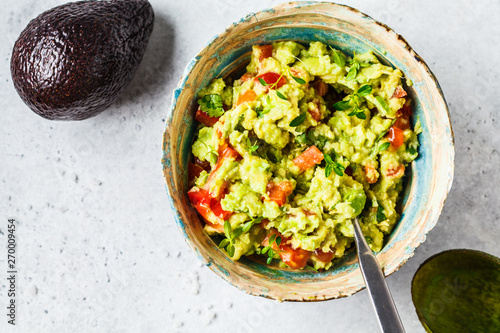 Fresh avocado tomato guacamole in a bowl. Healthy plant based food concept.