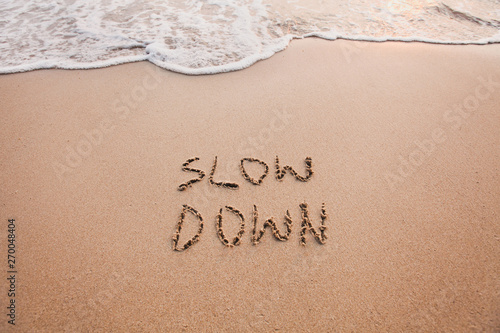 slow down, mindfulness concept written on sand