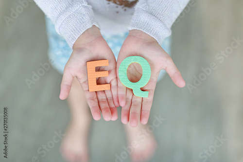 EQ (Emotional Quotient) sponge text on child hands. Education and development concept.