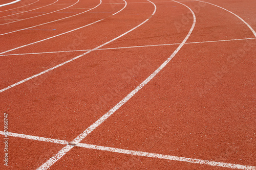 all-weather running track, rubberized artificial racing lane surface for track and field athletics, texture of white lines and curved in the stadium