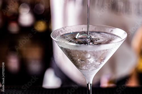 vodka martini isolated on a black background with an olive splashing and air bubbles