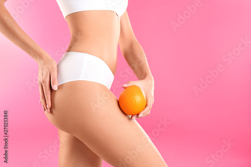 Closeup view of slim woman in underwear with orange on color background, space for text. Cellulite problem concept