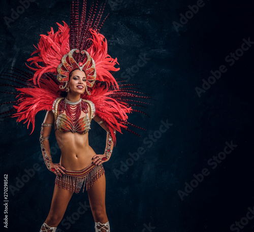 Szczęśliwy piękny tancerz Brasil w czerwonym kostiumie z piór tańczy na małej scenie.