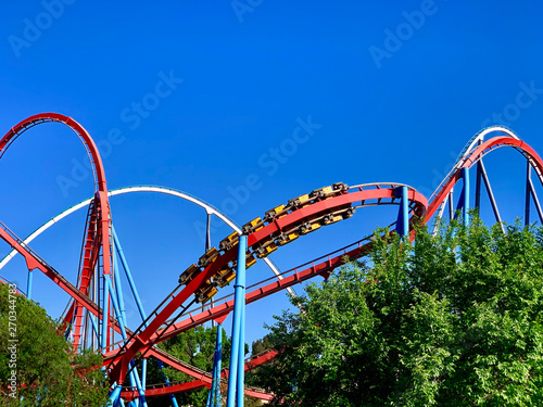 A red roller coaster in a amusement park with some loopings