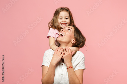 Woman in light clothes have fun with cute child baby girl. Mother, little kid daughter isolated on pastel pink wall background, studio portrait. Mother's Day, love family, parenthood childhood concept