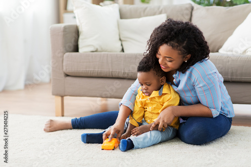 childhood, kids and people concept - happy african american mother and her baby son playing with toy car together on sofa at home