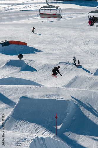 A snowboarder hitting his jump off the kicker in the snowpark