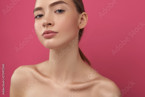 Attractive girl with perfect skin posing against pink background