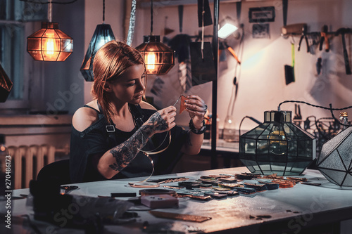 Busy diligent woman is working at lamp studio with tape and colourful triangles.