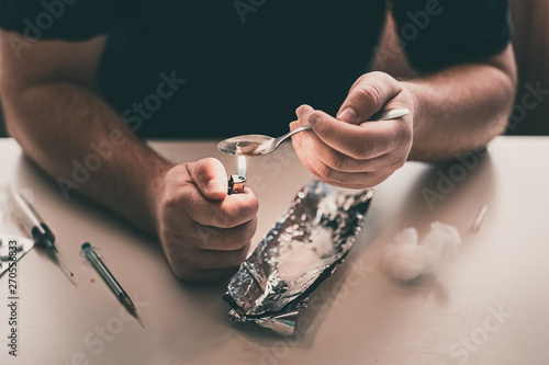 Addict at the table with a syringe heroin methamphetamine addiction