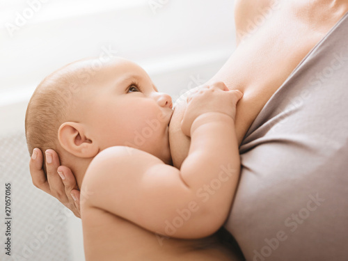 Mother breast feeding and hugging her baby