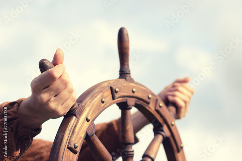 Steering hand wheel ship on sky background, hand hold hand wheel