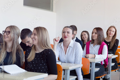 University students listening while Male professor explain lesson to them and interact with them in the classroom.Helping a students during class. 
